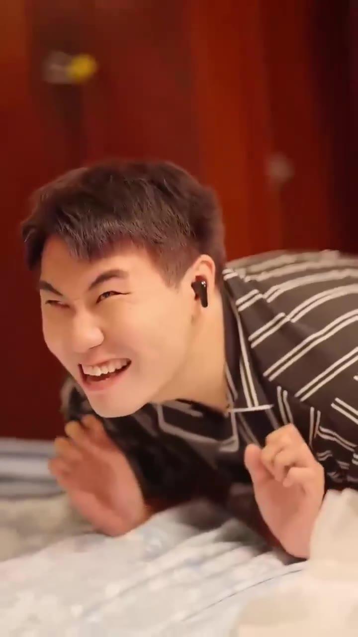 条纹睡衣男子戴耳机趴床大笑