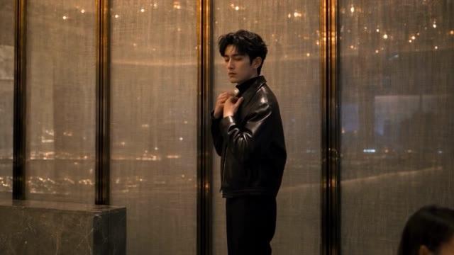 穿黑色外套的主线男子站在玻璃窗旁