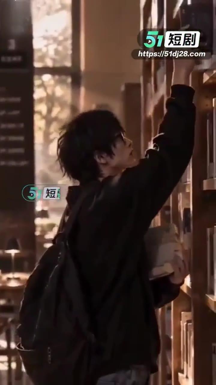 戴眼镜的男生在图书馆书架间取书