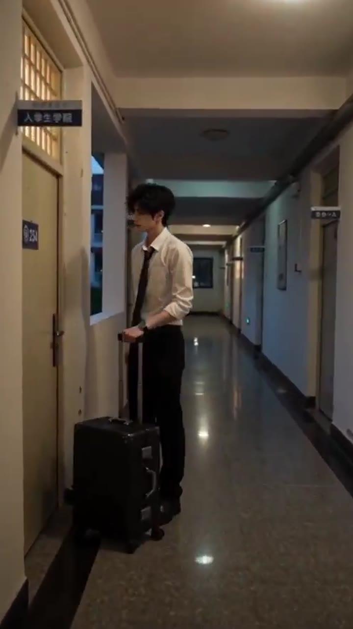 男生带行李走入大学宿舍走廊